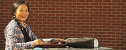 Woman sitting in front of a brick wall