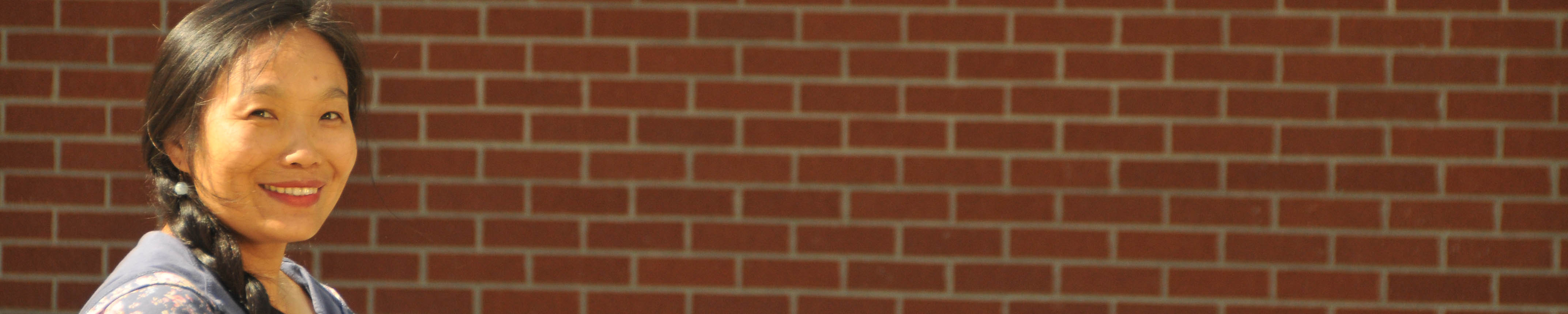 Asian woman in front of brick wall on college campus