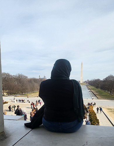 Baydaa sitting on the steps of the Lincoln Memorial looking at the Washington Monument