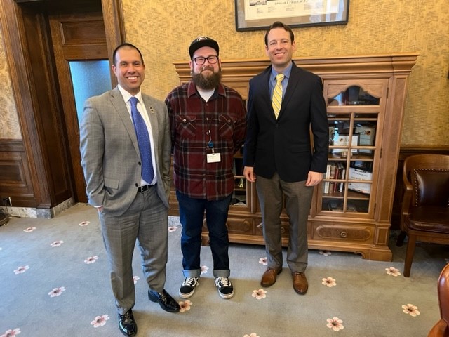 State Board Executive Director Paul Francis, State Board Legislative Intern Jacob Katz, and Sen. Andy Billig standing together in a room at the Legislative Building.