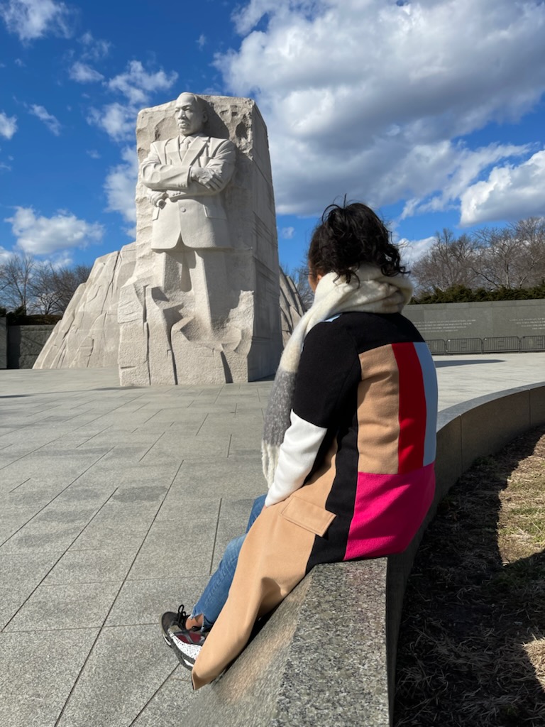 Melissa Littleton sitting by and looking at statue of Martin Luther King Jr. at the monument in Washington, DC.