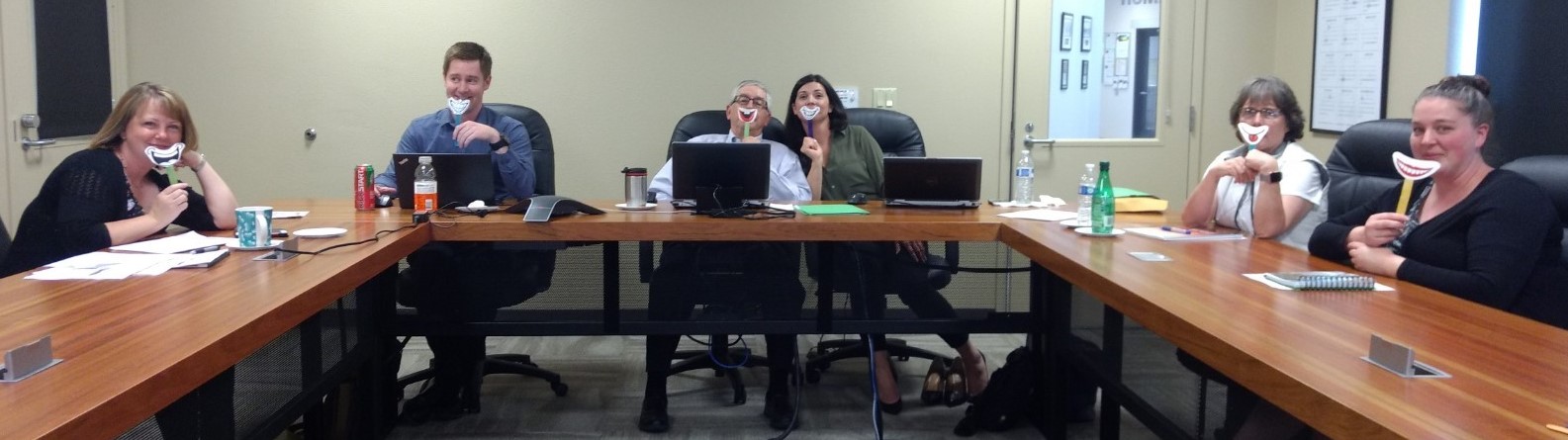 People at conference table each hold a Smile on a Stick