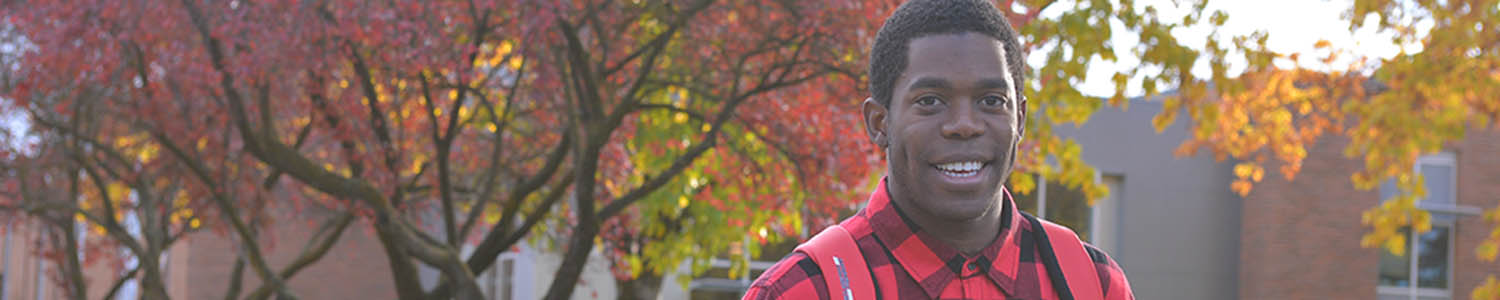 African-American man smiling among fall-colored trees