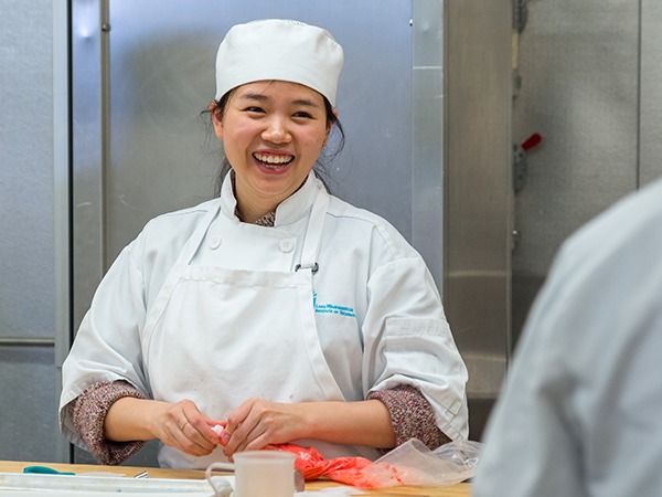 Culinary Arts student smiling while preparing food
